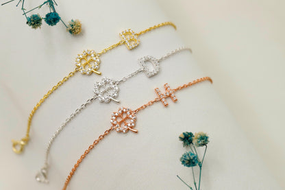 Three floral-themed bracelets in gold, silver, and rose gold on a light background with small flowers.