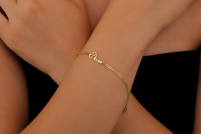 A close-up image of a person wearing a personalized name bracelet with a chain link design in silver.