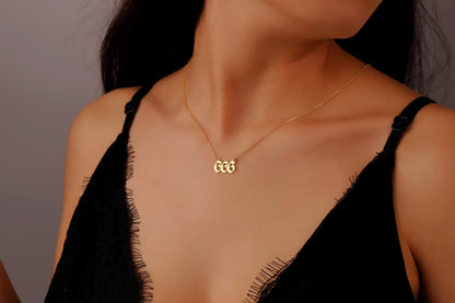 A close-up image of a person wearing a gold necklace with the number 666 on it.