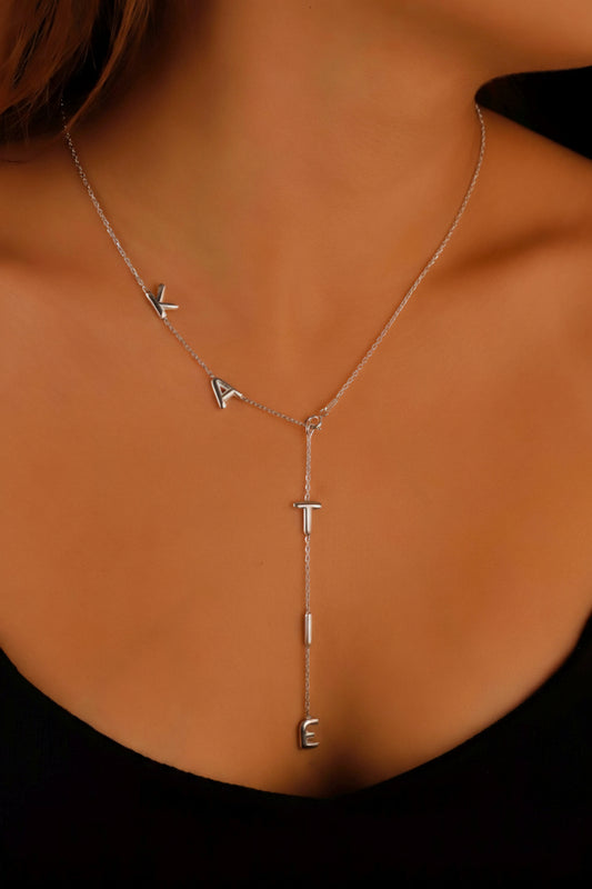 Silver necklace with geometric pendants on a person wearing a black top.