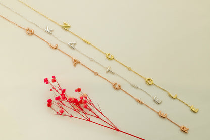 Set of gold necklaces with letter pendants on a light background