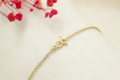 Gold bracelet on a light background with pink flowers