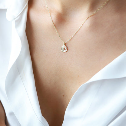 Gold necklace with a pendant on a person wearing a white shirt