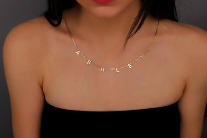 A sterling silver initial name necklace with gold finish, displayed on a person's neck.