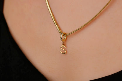 Gold necklace with a 'S' charm on a person's neck