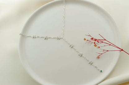 Silver necklace on a white plate with dried flowers