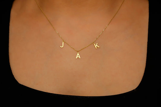 Gold necklace with 'JACK' pendant on a plain background