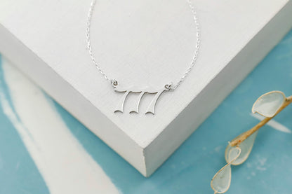 A close-up image of a necklace with the number 777 on a charm.