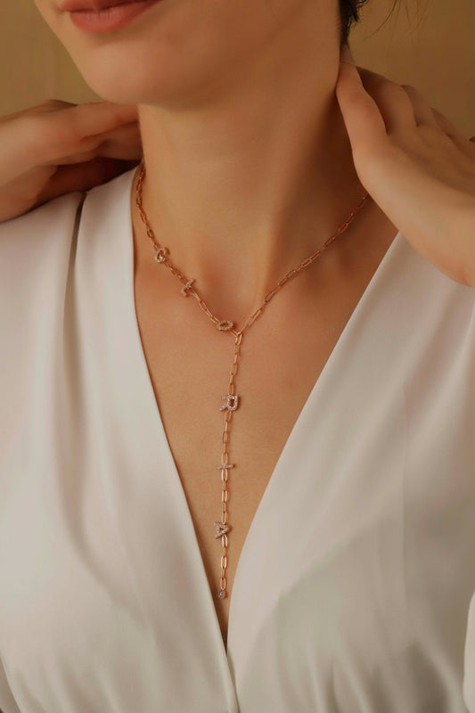 Rose gold necklace being worn by a person in a white top