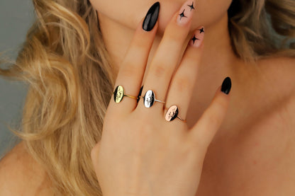 Close-up of a hand wearing multiple rings with black nail polish.