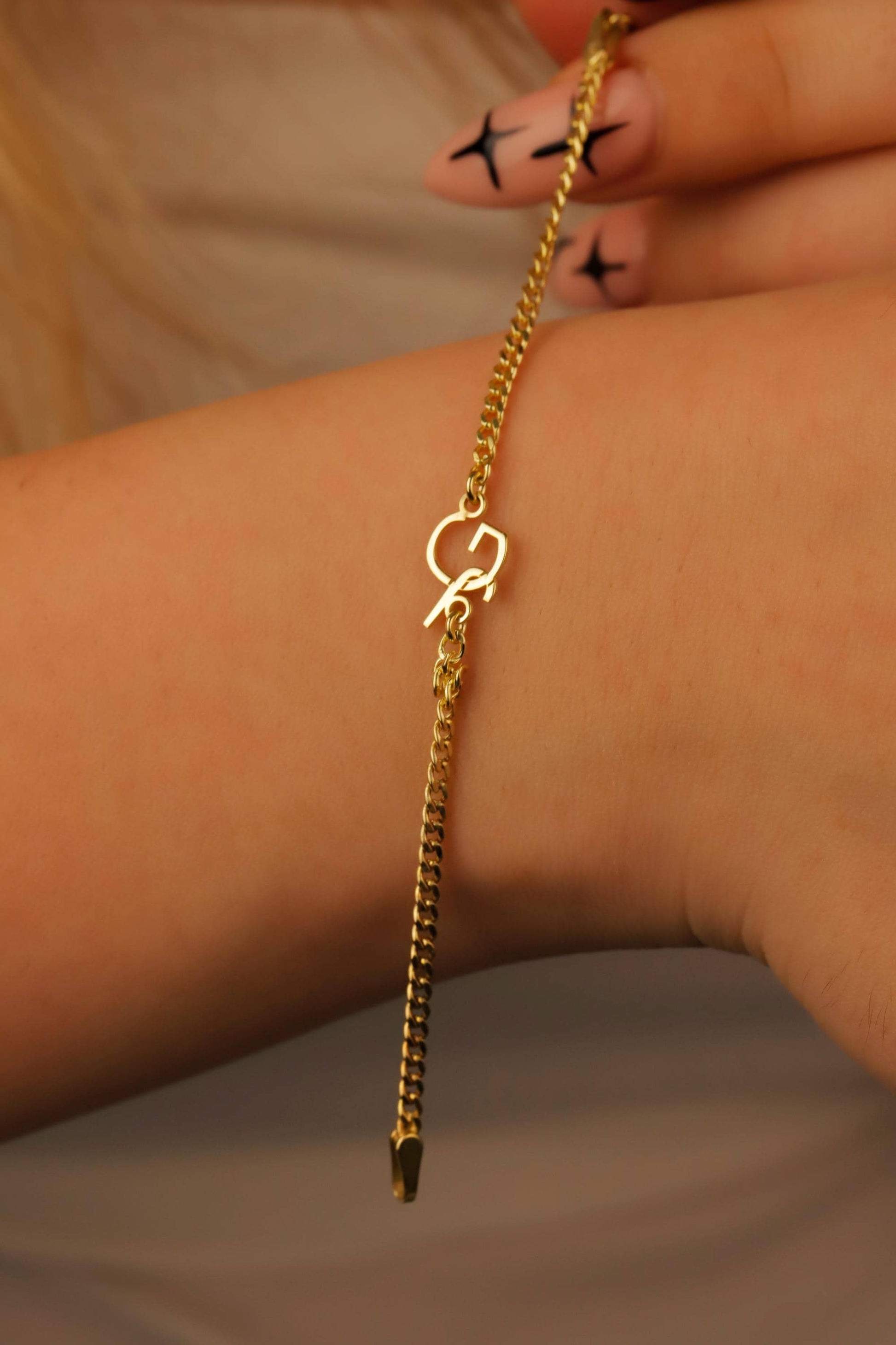 Gold chain bracelet on a wrist with a neutral background