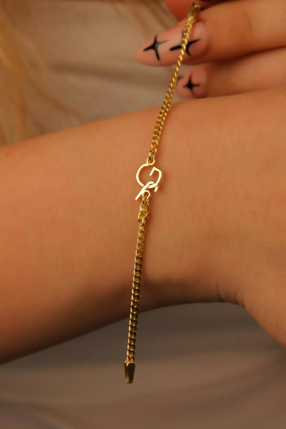 Gold chain bracelet on a wrist with a neutral background