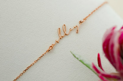 Rose gold necklace with 'ally' pendant on a light background