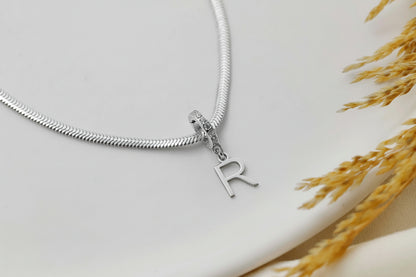 Silver necklace with a 'R' charm on a light background