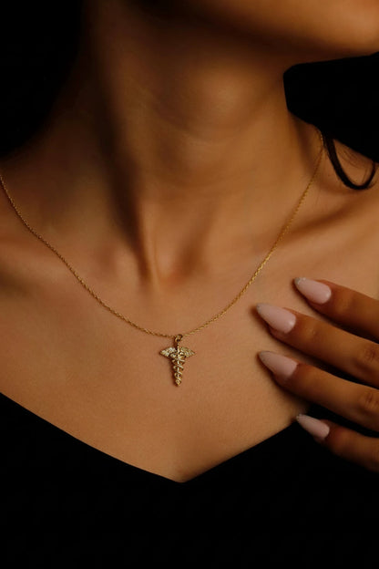 Necklace with a cross pendant worn by a person, with a hand touching the neck.