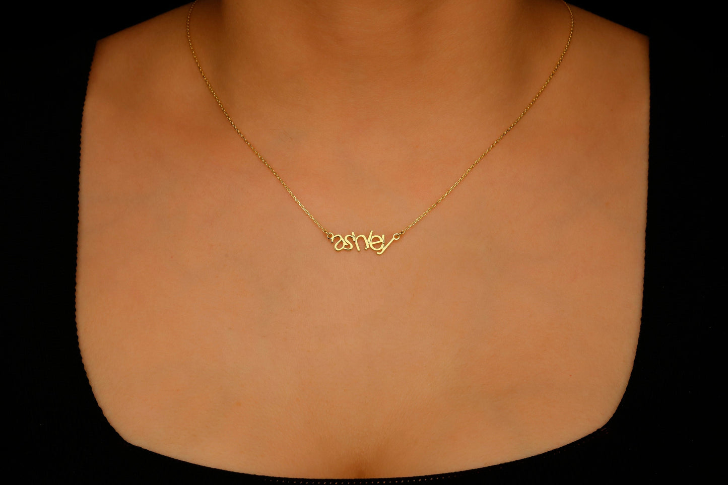 Gold necklace with a name pendant on a mannequin neck against a black background
