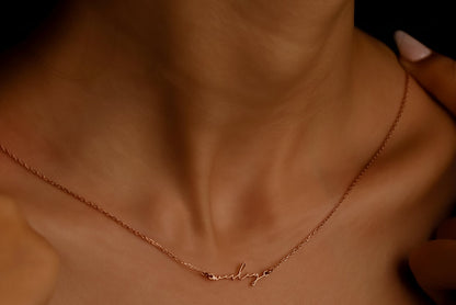 Rose gold necklace with 'always' engraving on a person's neck against a dark background