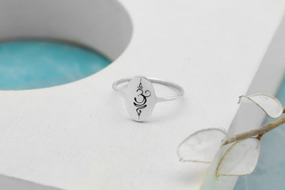 Silver ring with a symbol on a white surface with a light blue background
