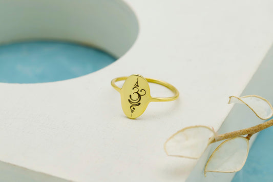 Gold ring with an engraved design on a light blue and white background