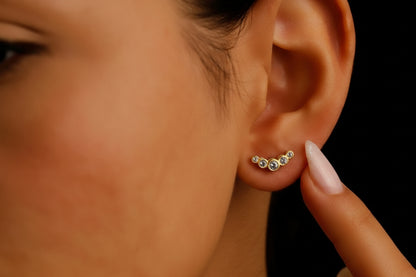 A close-up image of a woman's ear wearing a silver stud earring with a row of cubic zirconia stones.