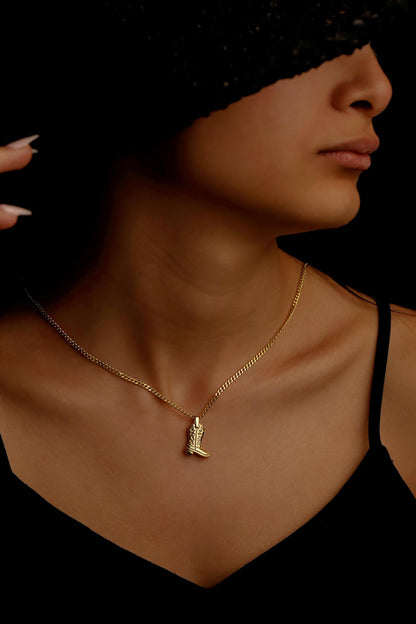 Woman wearing a gold necklace with a pendant against a dark background
