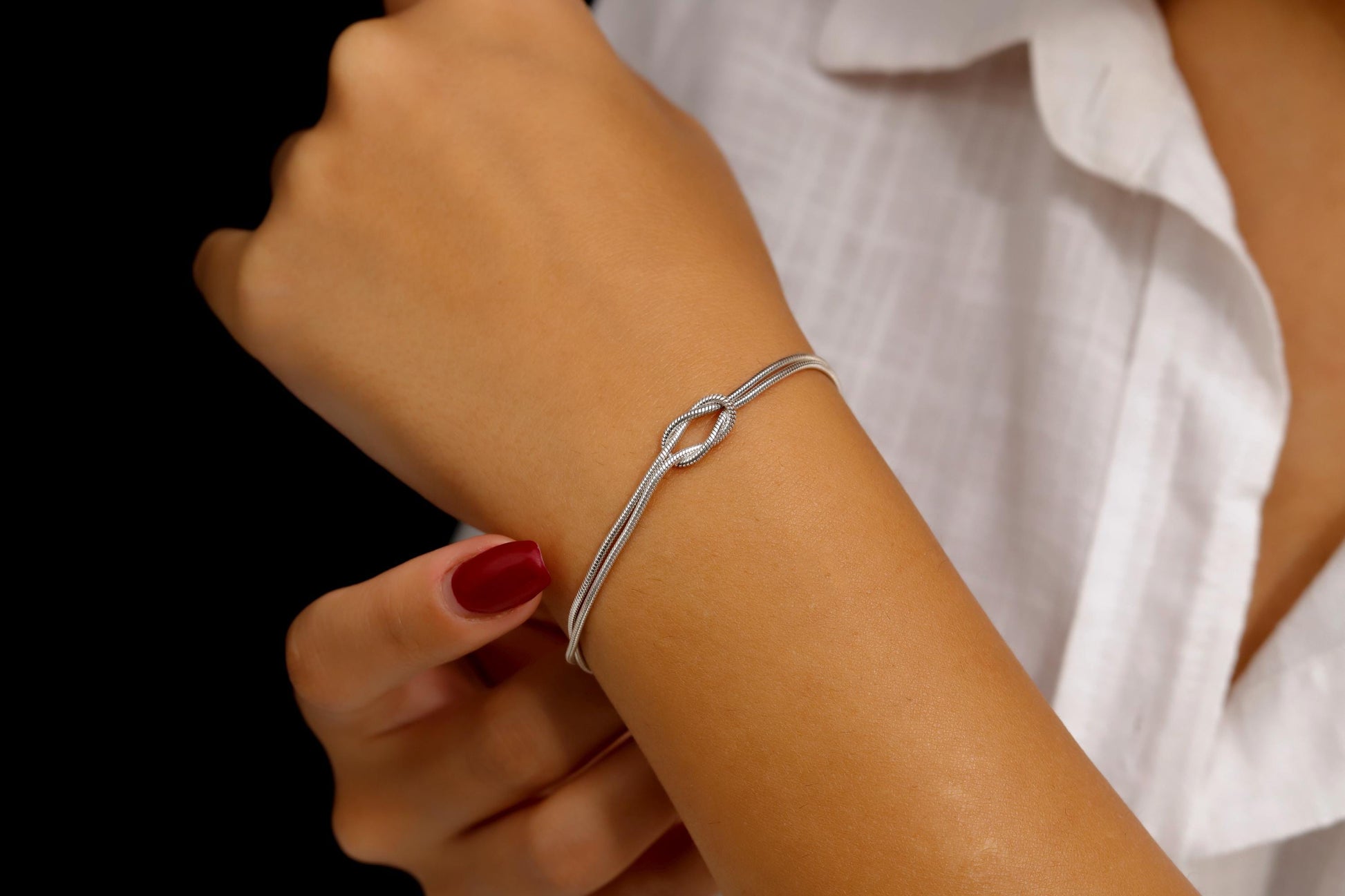 Silver bracelet on a wrist with a white shirt background