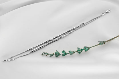 925 Sterling Silver Morse Code Bracelet with two strands hidden message, displayed on a white background next to a small green plant.