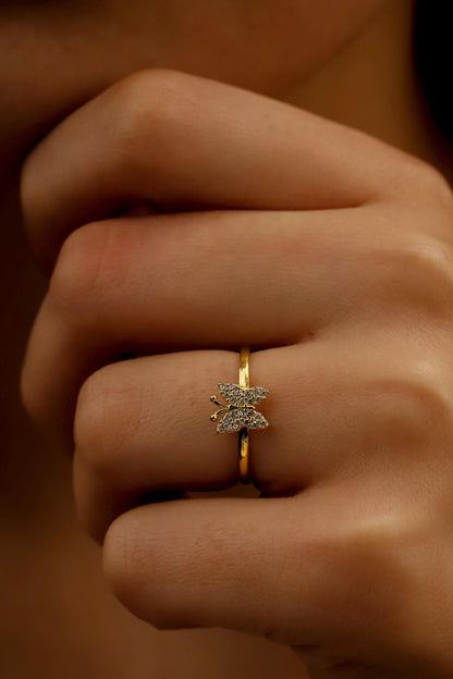 Close-up of a hand wearing a gold ring with a diamond design on a blurred background