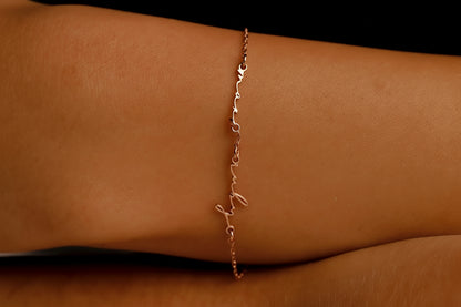 Rose gold anklet on a person's ankle against a dark background