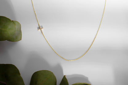a gold sideways cross necklace with a cz diamond.
