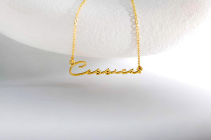 A gold name necklace with the name 'Carrie' displayed on a chain, presented against a white background.