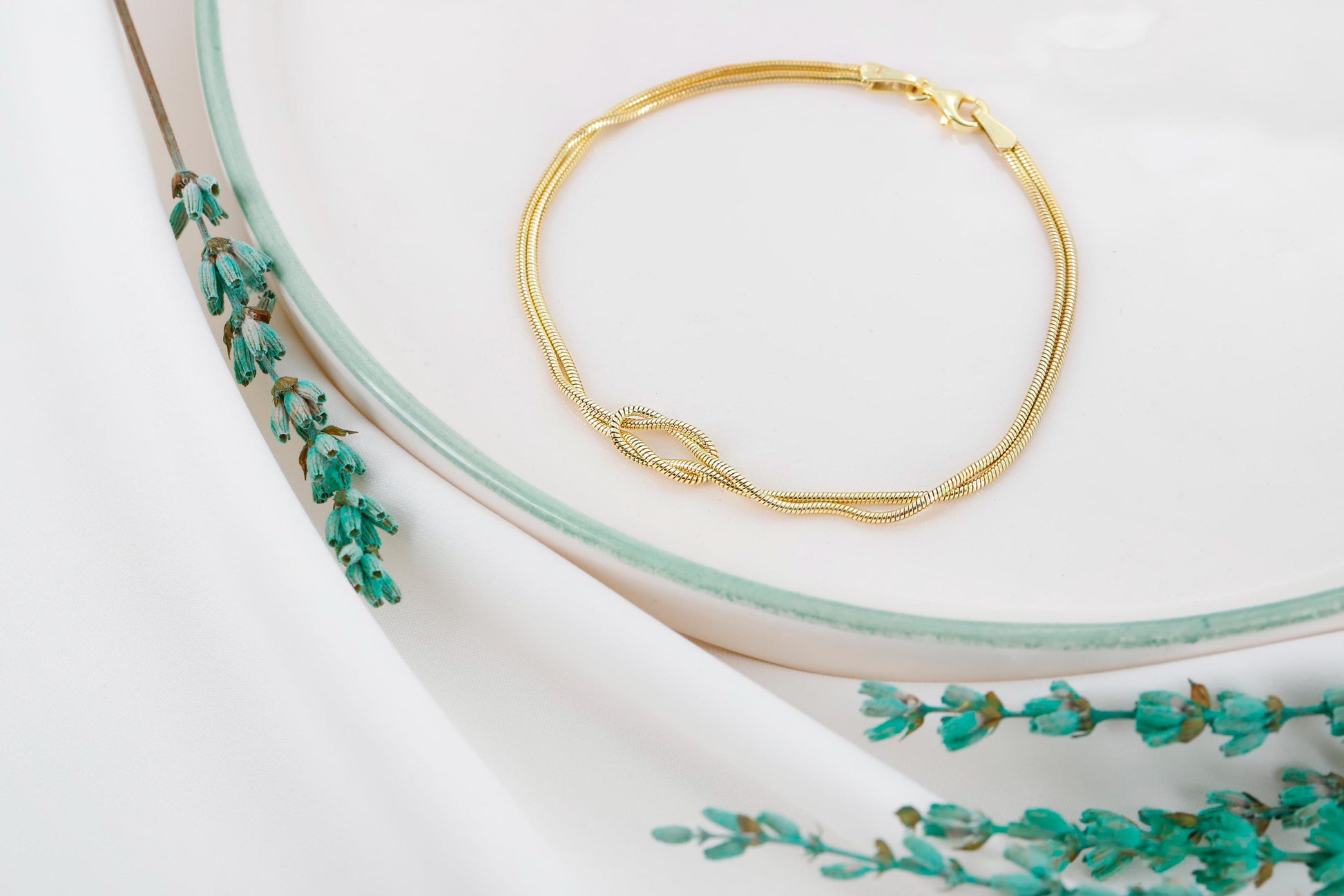Gold bracelet on a white surface with floral design