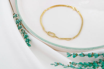 Gold bracelet on a white surface with floral design