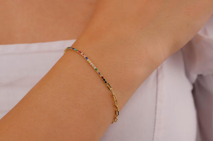 A colorful tennis bracelet with gold accents and multicolored gemstones displayed on a person's wrist.