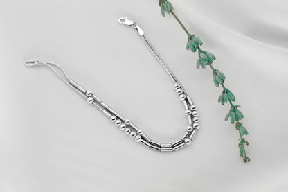 925 Sterling Silver Morse Code Bracelet with two strands hidden message, displayed on a white background next to a small green plant.