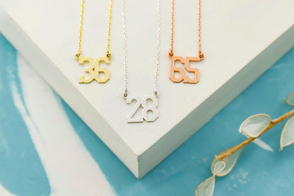 Three necklaces with numbers on a white box with a blue background