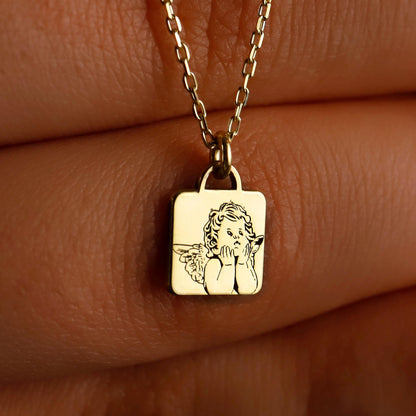A close-up image of a gold-colored necklace with a personalized pendant, displaying the engraved text 'guardian angel' on a person's skin.