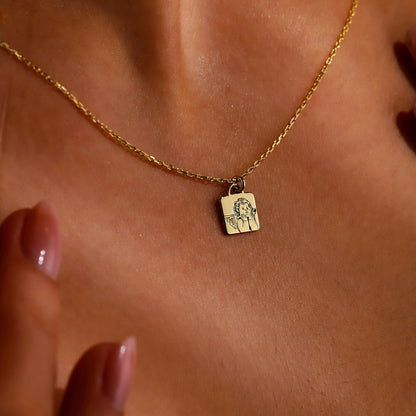 A close-up image of a gold-colored necklace with a personalized pendant, displaying the engraved text 'guardian angel' on a person's skin.
