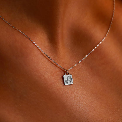 A close-up image of a gold-colored necklace with a personalized pendant, displaying the engraved text 'guardian angel' on a person's skin.