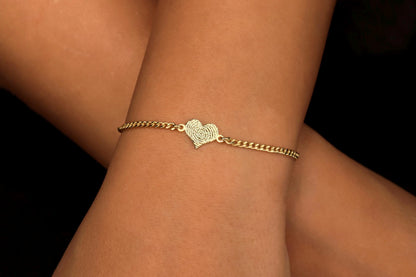 A gold bracelet with a fingerprint engraving on a person's wrist.