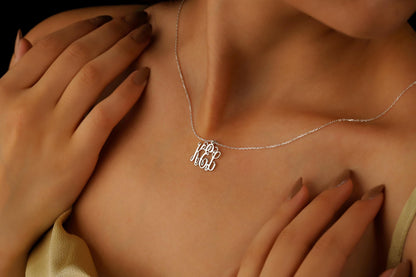 A close-up image of a gold monogram necklace on a person's neck, highlighting the delicate and elegant design of the pendant.