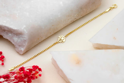 A close-up image of a gold-filled bracelet with a block monogram initial pendant.