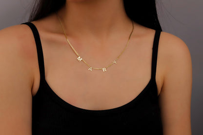 A sterling silver initial name necklace with gold finish, displayed on a person's neck.