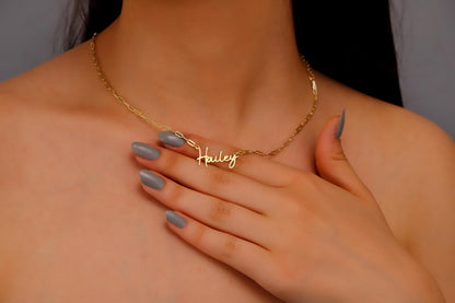 A person wearing a gold name necklace with the name 'Hailey' displayed on the chain.