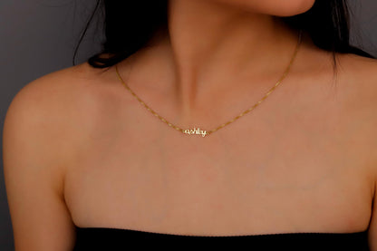 A person wearing a dainty gold tiny name necklace with a box chain.