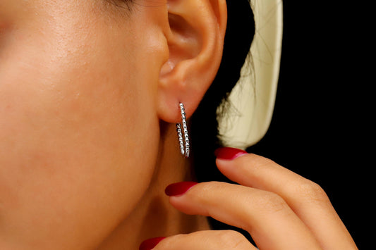 Close-up of a person wearing hoop earrings with a black background