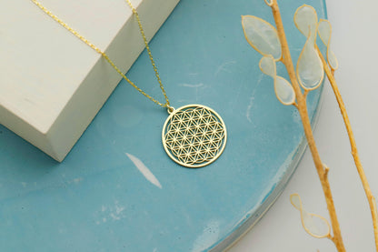 Gold necklace with a geometric pendant on a blue surface