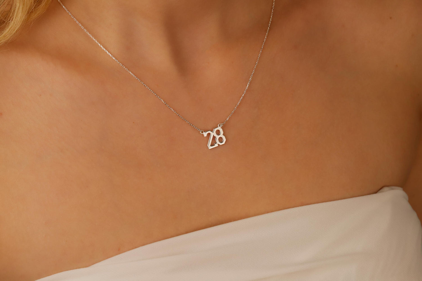 Necklace with a '28' pendant on a person's neck