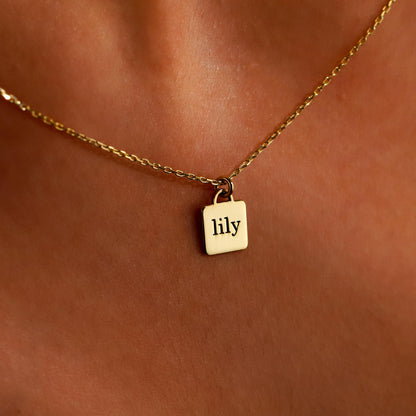 A close-up image of a gold-colored necklace with a personalized pendant, displaying the engraved text 'guardian angel' on a person's skin.