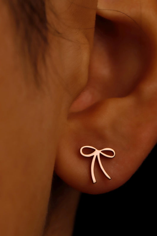 Gold bow-shaped earring on a person's ear